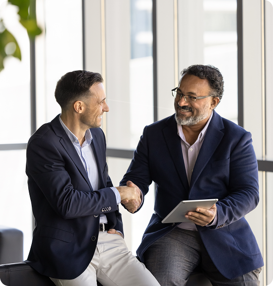 Two men shaking hands, one holding tablet.